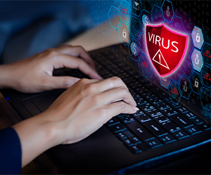 Hands typing on laptop with virus warning graphic
