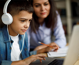 Child using a laptop with parent nearby